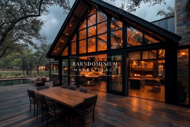 A stunning modern rustic home with large glass walls, warm interior lighting, and a spacious outdoor dining area on a wooden deck, perfect for entertaining.