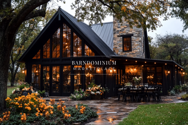 A stunning modern-rustic barndominium with floor-to-ceiling glass windows, warm interior lighting, and a beautifully landscaped outdoor dining area.