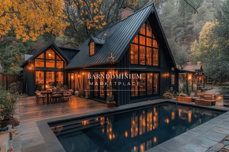 A modern black barndominium nestled in the woods, featuring a sleek metal roof, warm glowing windows, and a luxurious pool reflecting the autumn foliage.