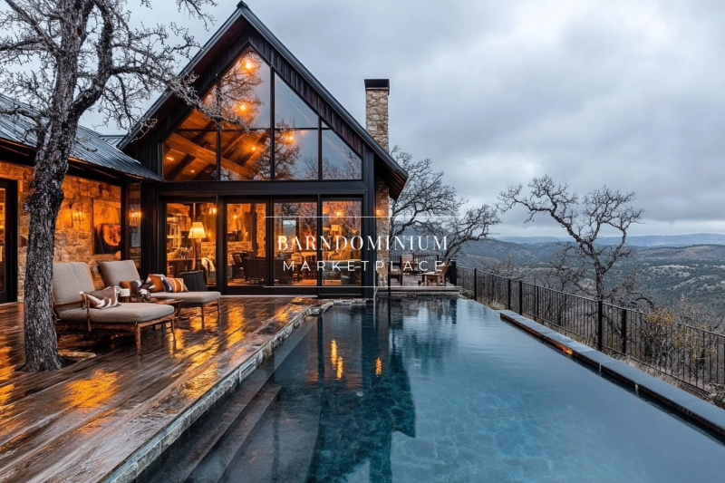 A stunning modern barndominium with an infinity pool, floor-to-ceiling windows, and warm interior lighting, offering breathtaking hillside views.