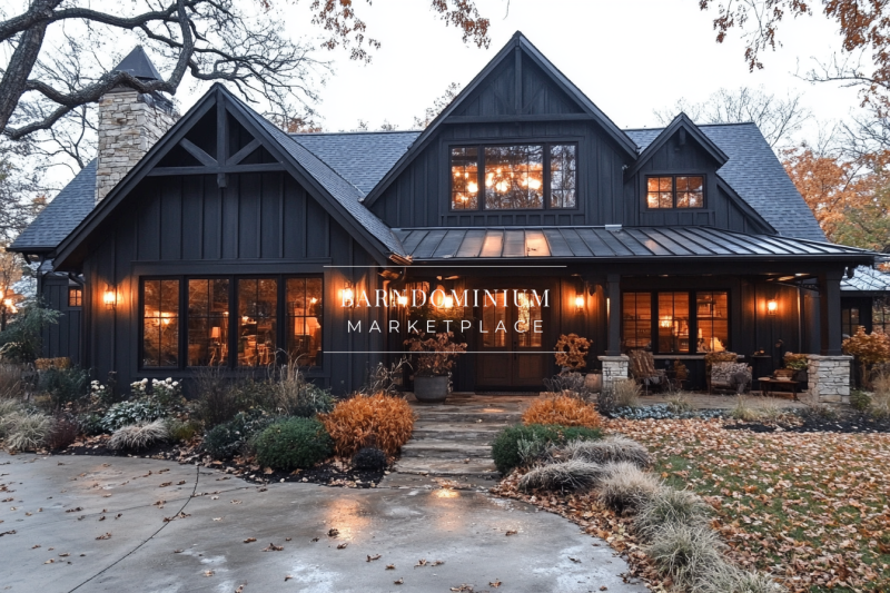 A stunning black barndominium with warm glowing lights, a welcoming front porch, and autumn-inspired landscaping, creating a cozy farmhouse feel.