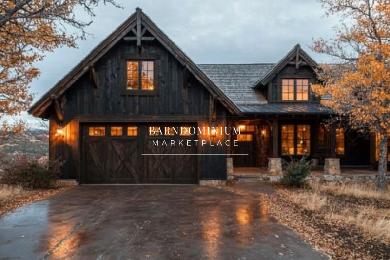 A stunning dark wood barndominium with warm glowing lights, a spacious garage, and a cozy rustic charm, set against an autumn landscape.