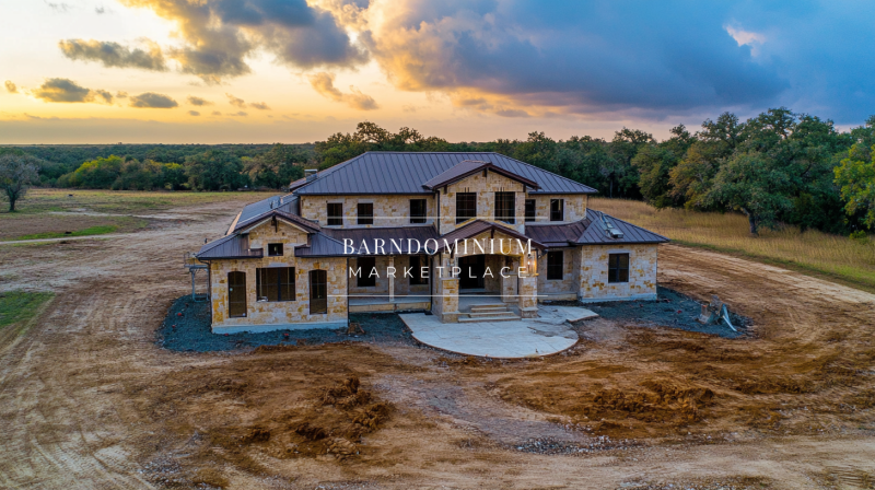 A stunning barndominium with rustic stone exterior and a modern metal roof, set against a breathtaking sunset.