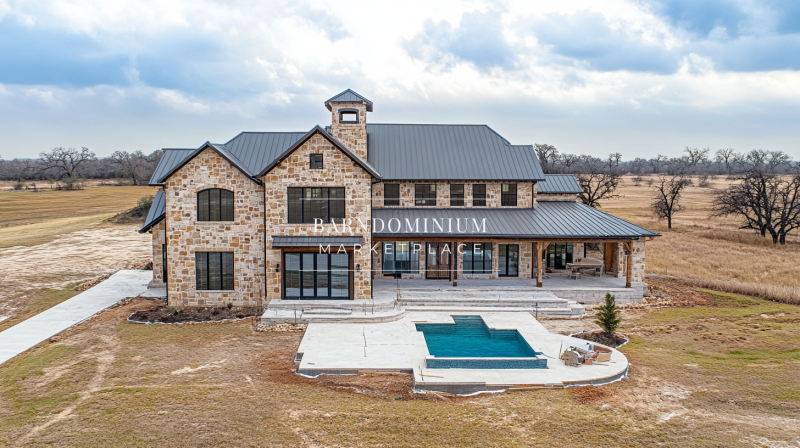 Luxurious barndominium with stone exterior, black metal roof, and a backyard pool, blending rustic charm with modern elegance.