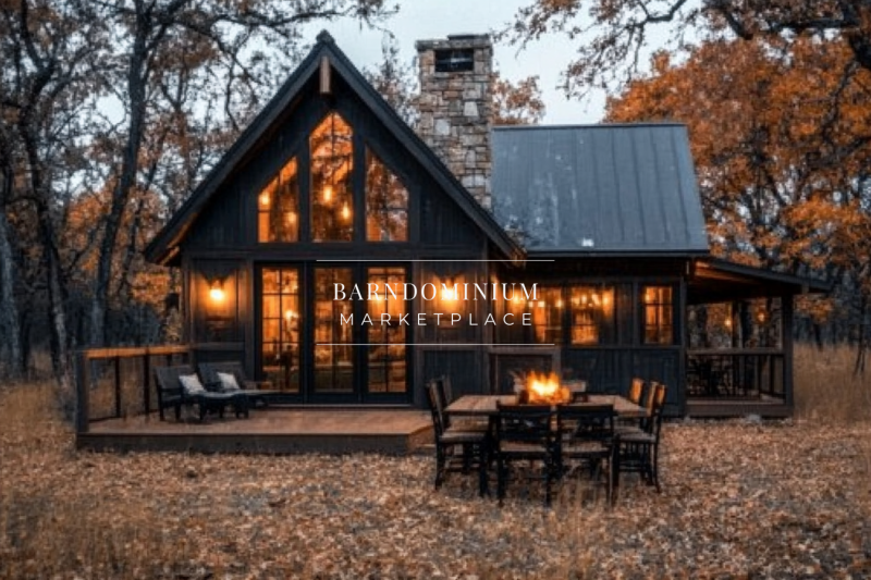 Charming barndominium exterior with a dark rustic finish, stone chimney, and glowing lights, creating a cozy autumn retreat.