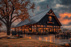 A stunning modern barndominium-style restaurant with warm interior lighting, a sleek black metal roof, and a rustic ambiance, set against a dramatic sunset sky.