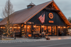 A charming black barn-style storefront with warm lighting, rustic decor, and an American flag, creating a cozy and inviting atmosphere.