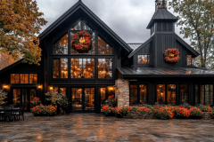 A charming black barndominium adorned with festive wreaths and warm lighting, surrounded by vibrant autumn flowers, creating the perfect cozy holiday retreat.