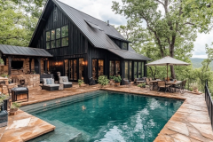 A modern black barndominium nestled in nature, featuring a serene poolside retreat, rustic stone patio, and cozy outdoor living space.