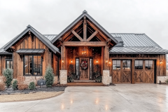 Charming rustic-modern barndominium with exposed wood beams, stone accents, and a cozy front porch, perfect for country living.
