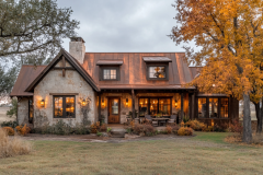 Rustic barndominium with a copper roof, stone exterior, and warm autumn-inspired lighting.
