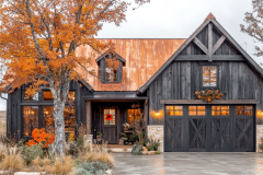 Charming black barndominium with a copper roof, warm lighting, and autumn-inspired landscaping.