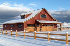 A stunning red barndominium in a snowy landscape, combining rustic charm with modern living.