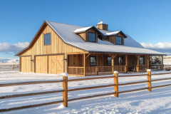 A rustic wooden barndominium covered in snow, offering a cozy countryside retreat.