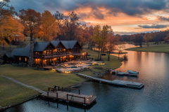A luxurious lakeside barndominium at sunset, featuring rustic charm, glowing lights, and a peaceful waterfront dock.