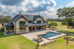A luxurious barndominium with a modern farmhouse design, featuring a sleek black roof, expansive patio, and stunning backyard pool.