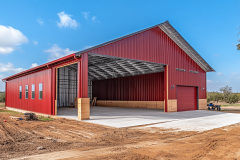 A bold red barndominium with an open garage, showcasing its spacious and functional design.