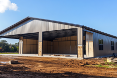 Steel barndominium exterior with an open front design, stone accents, and a spacious interior layout.