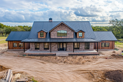 Spacious barndominium exterior with a classic farmhouse design, wooden accents, and a welcoming front porch.