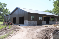 Barndominium under construction with a steel exterior and open garage bays.
