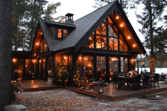 Elegant barndominium exterior with large glass windows, warm outdoor lighting, and a stylish wooden deck, creating a cozy and inviting atmosphere.