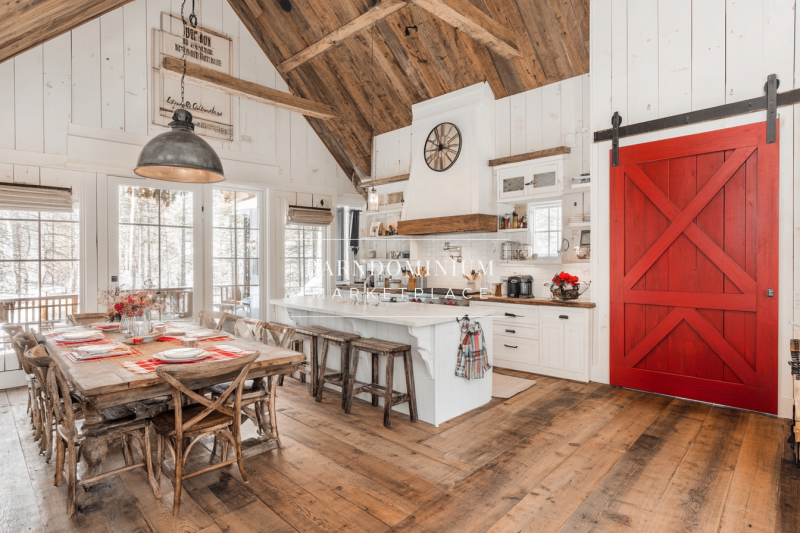 Bright farmhouse-style barndominium kitchen with a bold red barn door.