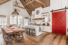 Bright farmhouse-style barndominium kitchen with a bold red barn door.