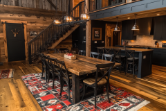 Rustic barndominium kitchen and dining area with a farmhouse-style wooden table and warm, cozy lighting.
