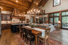 Elegant barndominium interior featuring an open-concept kitchen, rustic wood beams, and a farmhouse-style dining area with warm lighting.