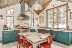 A charming farmhouse-style barndominium kitchen with distressed turquoise cabinetry, white shiplap walls, rustic wood accents, and vintage-inspired red dining chairs.