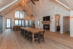 A bright and airy barndominium interior with a vaulted ceiling, white shiplap walls, rustic wood accents, and an open dining area perfect for farmhouse-style living.