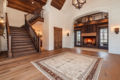 Elegant entryway with a grand staircase, warm wood tones, and a cozy fireplace.