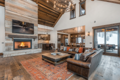 Rustic yet modern barndominium living room featuring high ceilings, a cozy fireplace, and an open-concept design with warm wood tones and elegant decor.