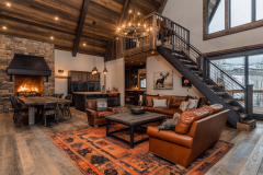 Warm and inviting barndominium interior featuring a lofted second level, rustic wood accents, a stone fireplace, and cozy leather furniture for a modern lodge feel.