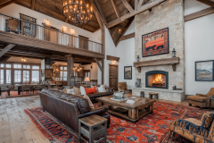 Stunning barndominium interior featuring a grand stone fireplace, exposed wood beams, and a spacious open-concept living area with rustic Western-inspired décor.