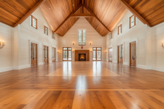 Elegant barndominium interior featuring a vaulted wood ceiling, grand fireplace, and an open-concept design with warm natural lighting and classic French doors.