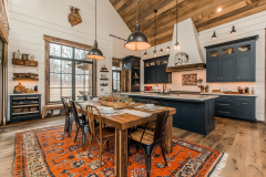 Stunning barndominium kitchen with rustic wood accents, bold navy cabinetry, and an inviting farmhouse dining area.