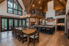 A stunning barndominium interior featuring vaulted ceilings, rustic wood beams, an open kitchen, and a spacious dining area with a chandelier.