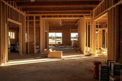 Framing stage of a barndominium construction project, showcasing wooden beams, open layouts, and natural lighting.