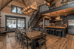 Elegant barndominium interior with a rustic dining area, open kitchen, and loft-style second floor.