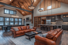 Stunning barndominium living space with vaulted wood ceilings, leather seating, and an open-concept kitchen.