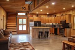 Cozy barndominium interior with warm wood finishes, an open kitchen layout, and a lofted second level.