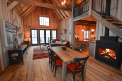 Warm and inviting barndominium interior with high vaulted ceilings, natural wood finishes, and a cozy fireplace.